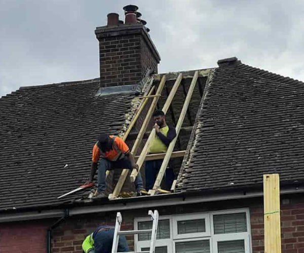 This is a photo of a roof repair being carried out. A section of the roof has been stripped and two roofers are replacing the rafters. Works being carried out by WCT Roofing Long Buckby